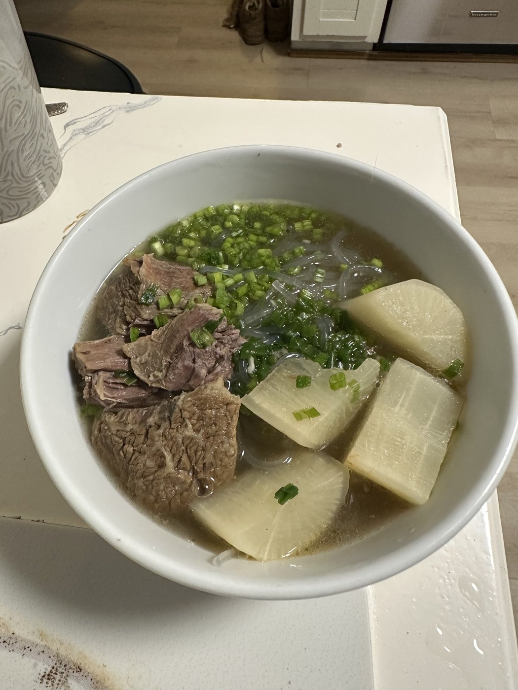 Bowl of beef and radish soup with glass noodles and scallions